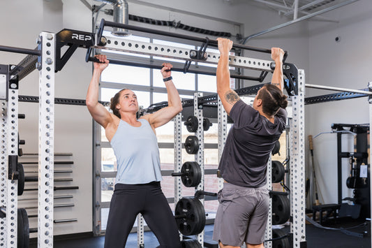 Two athletes do pull-ups.