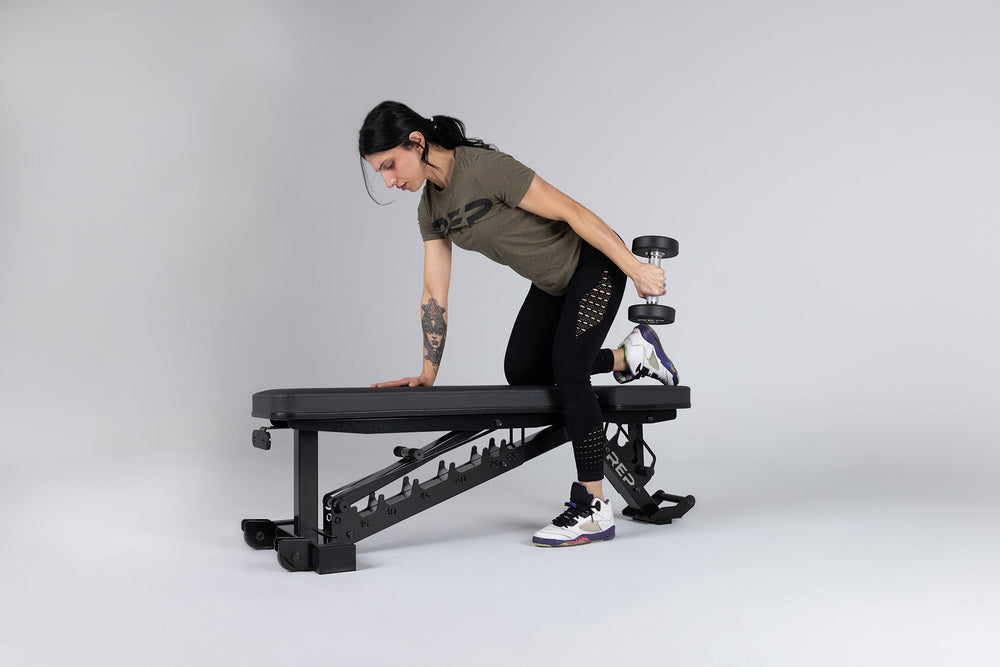 Athlete uses a REP bench to do tricep kickbacks.