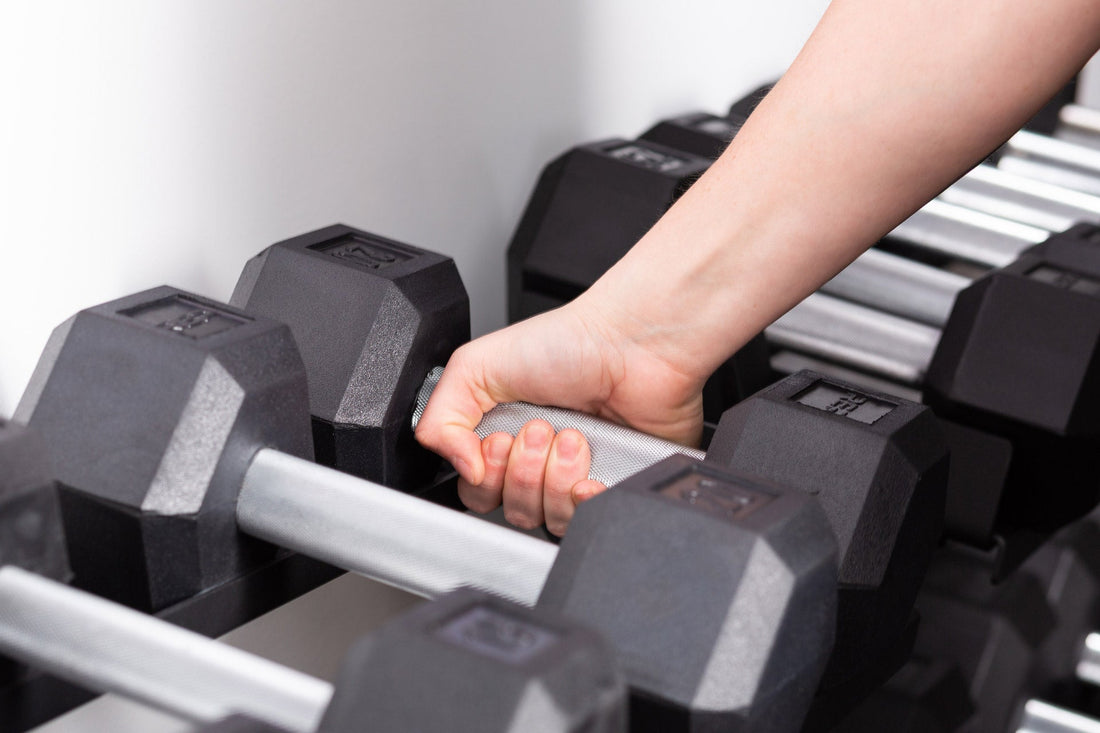 Hand picking up a fixed dumbbell from a dumbbell rack