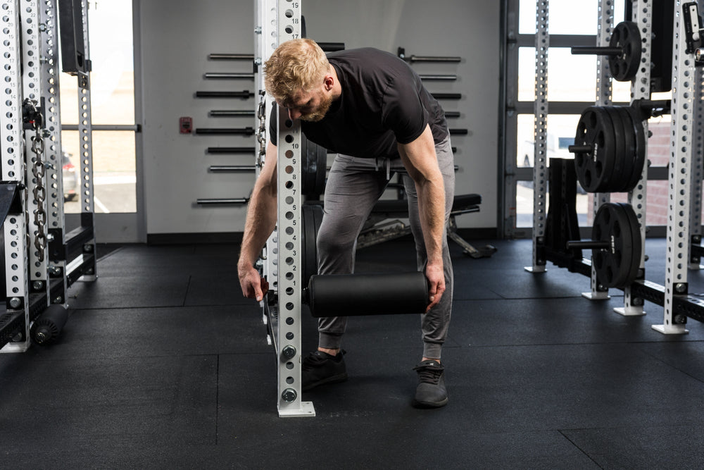 Athlete attaches leg roller to upright.