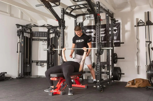 Athlete tackles bench press with a spotter.