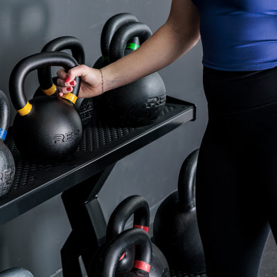 Athlete grabbing a kettlebell off of the REP Fitness 2-Tier Kettlebell Rack 2.0
