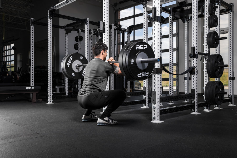 Athlete front squatting a barbell with Black Competition Bumper Plates (KG)
