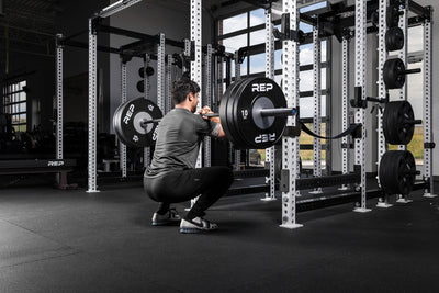 Athlete front squatting a barbell with Black Competition Bumper Plates (KG)