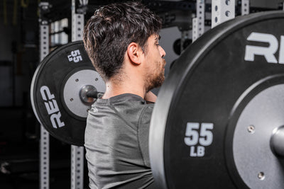 Athlete holding a barbell with Black Competition Bumper Plates (LB) in a front rack position
