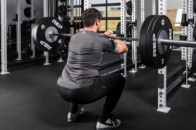 Athlete front squatting a barbell with Black Competition Bumper Plates (LB)