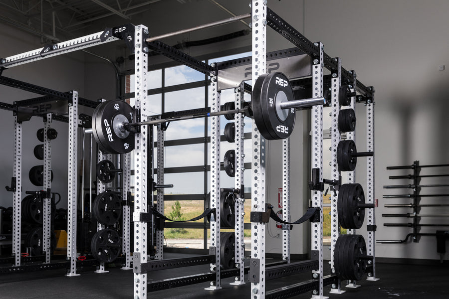 Black Competition Bumper Plates (LB) loaded onto a barbell racked on a PR-5000 rack