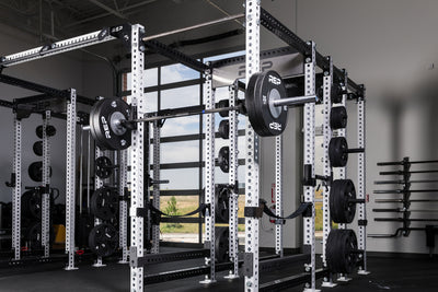 Black Competition Bumper Plates (LB) loaded onto a barbell racked on a PR-5000 rack