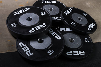 Black Competition Bumper Plates (KG) laying on a lifting platform