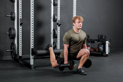 Athlete doing a dumbbell split squat with the Altitude™ Leg Roller on the Power Rack
