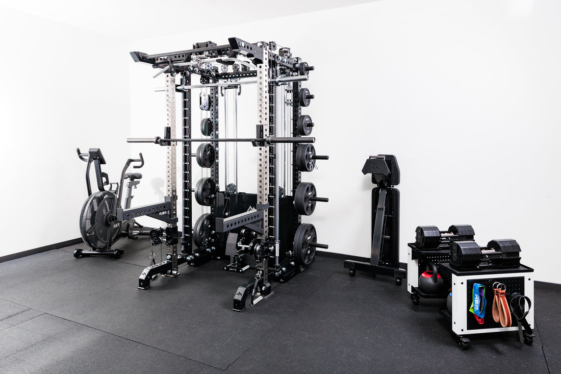 Gym equipment including a Smith machine rack attachment and weight rack on a black floor with white walls.