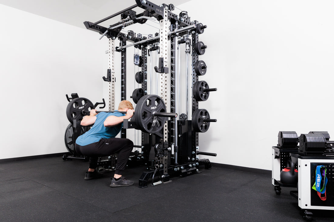 Person performing squats off the front of the Summit™ All-In-One Ares™ 2.0 configuration in a gym setting.