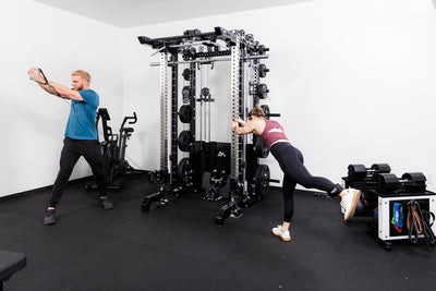 Two people performing cable machine exercises on the Summit™ All-In-One Ares™ 2.0 Upgrade Kit  in a gym setting.