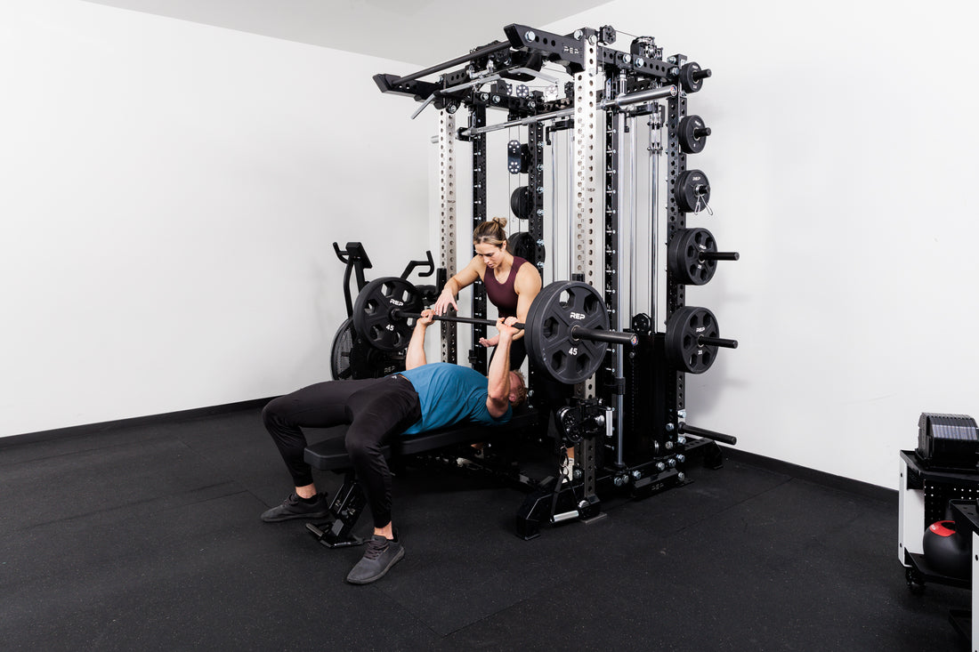 Person performing bench press with a spotters off the front of the Summit™ All-In-One Ares™ 2.0 Upgrade Kit  in a gym setting.