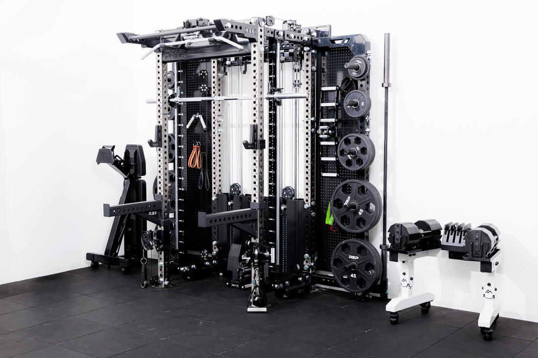 Gym equipment including a Smith machine rack attachment  on a Summit™ All-In-One Ares™ 2.0 Wall-Mounted and weight rack on a black floor with white walls.