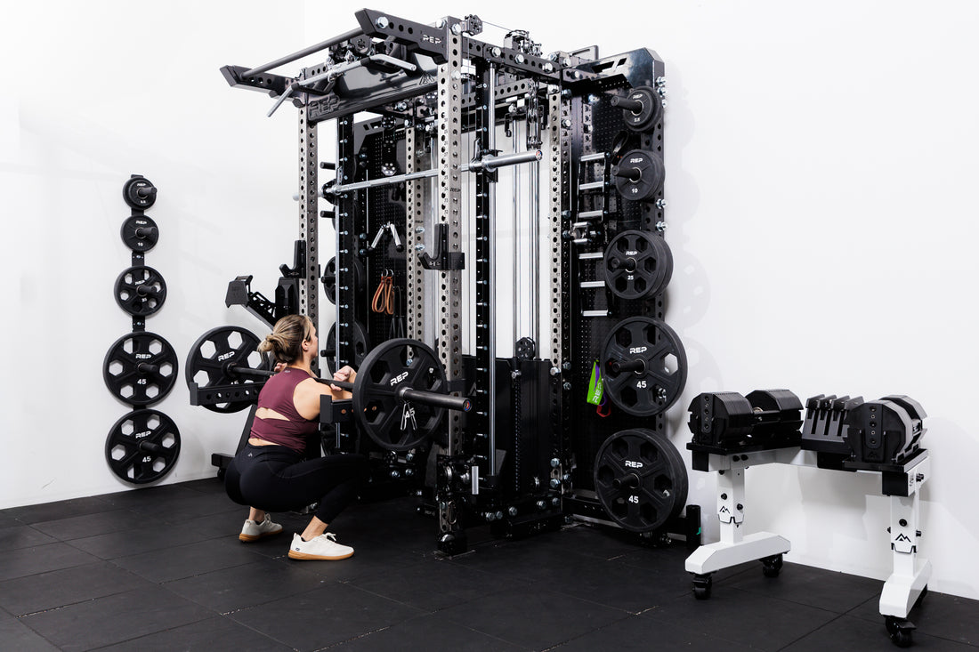Person performing front squats off the front of the Summit™ All-In-One Ares™ 2.0 Wall-Mounted configuration in a gym setting.