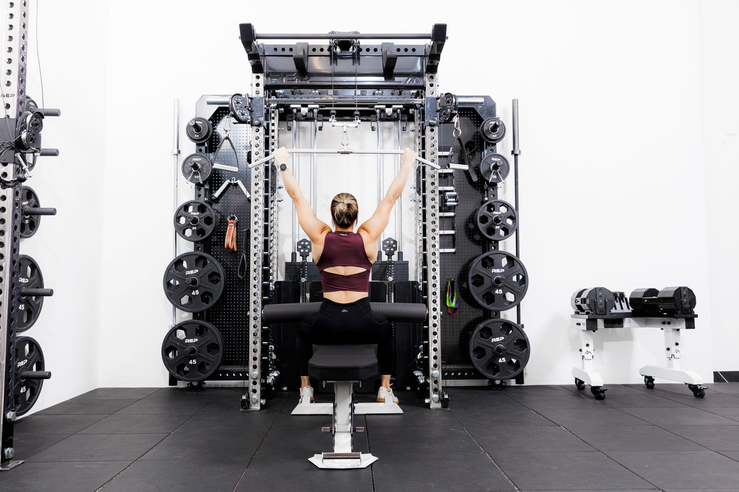 Person using the Ares™ 2.0 for lat pulldowns on the Summit™ All-In-One Ares™ 2.0 Wall-Mounted configuration in a gym setting.
