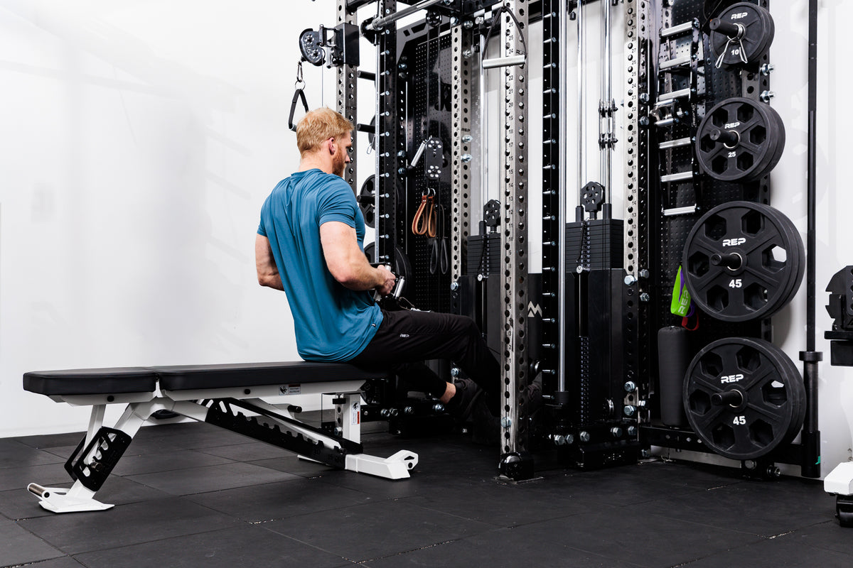 Person using the Ares™ 2.0 for low rows on the Summit™ All-In-One Ares™ 2.0 Wall-Mounted configuration in a gym setting.