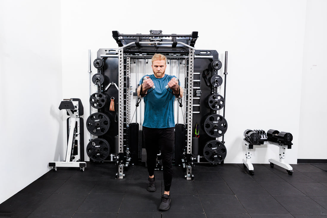 Person using the Ares™ 2.0 for cable machine exercises on the Summit™ All-In-One Ares™ 2.0 Wall-Mounted configuration in a gym setting.