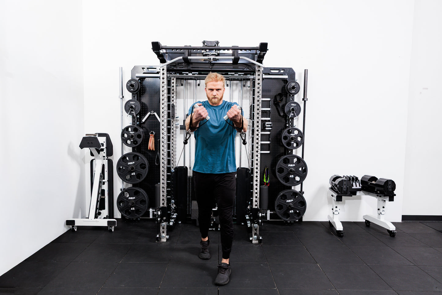 Person using the Ares™ 2.0 for cable machine exercises on the Summit™ All-In-One Ares™ 2.0 Wall-Mounted configuration in a gym setting.
