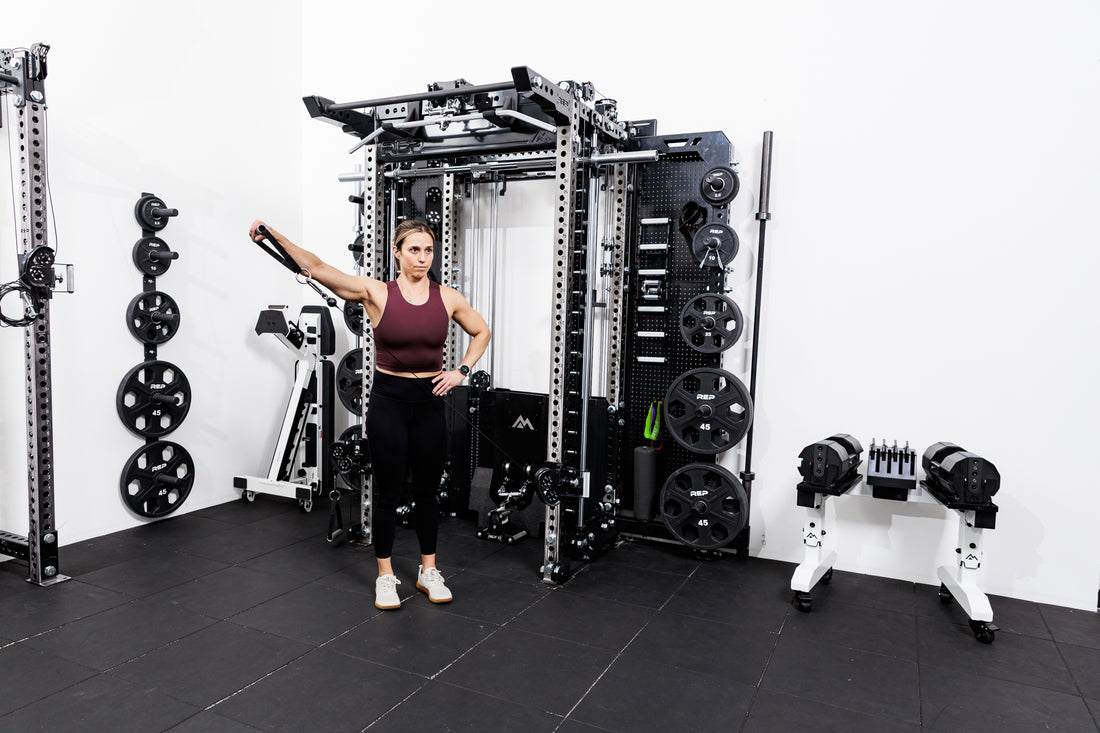 Person using the Ares™ 2.0 for cable side raises on the Summit™ All-In-One Ares™ 2.0 Wall-Mounted configuration in a gym setting.