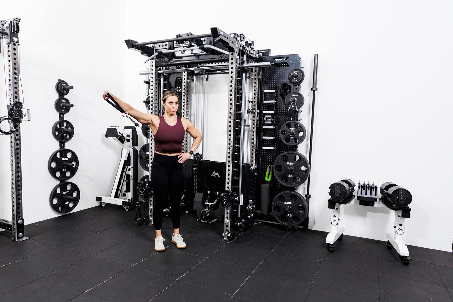 Person using the Ares™ 2.0 for cable side raises on the Summit™ All-In-One Ares™ 2.0 Wall-Mounted configuration in a gym setting.