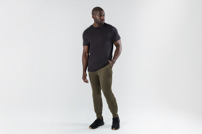 The REP Fitness Men's Attis Joggers in Heather Olive front, black tee, hand in pocket