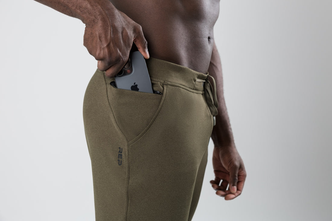 The REP Fitness Men's Attis Joggers in Heather Olive front, phone pocket detail