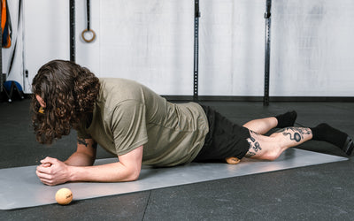 Action-shot: Athlete targeting a pressure point on their leg by rolling the REP Cork Massage Ball against the floor.