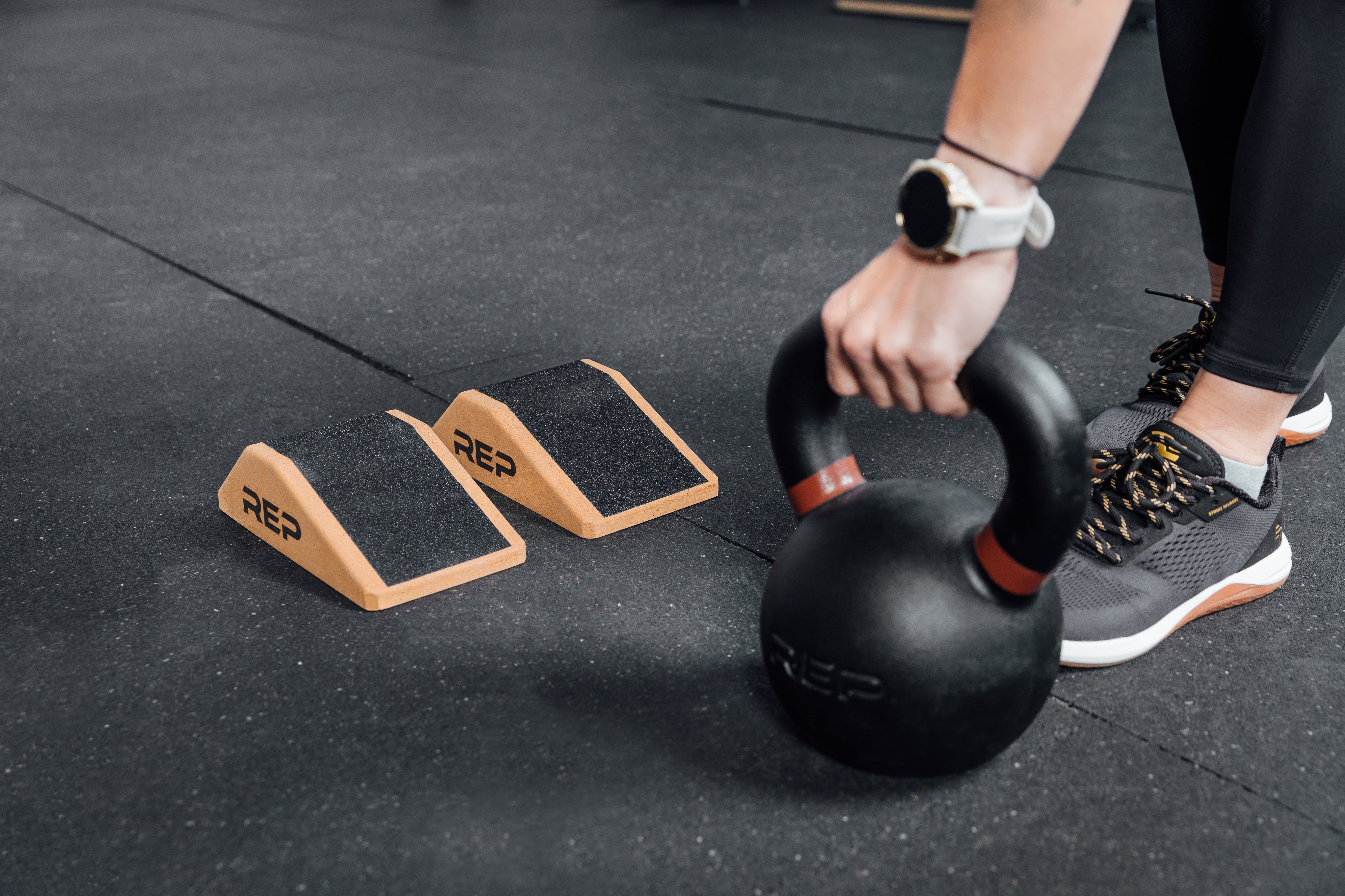 Athlete lifting a kettlebell next to Cork Squat Wedges