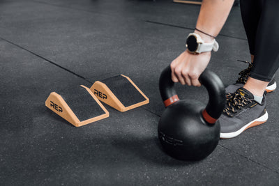 Athlete lifting a kettlebell next to Cork Squat Wedges