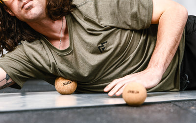 Close-up: Athlete targeting a pressure point on their chest by rolling the REP Cork Massage Ball against the floor.