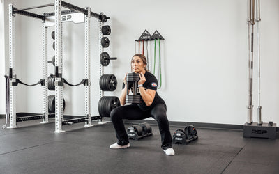 Female lifter performing a goblet squat with a single REP Fitness QuickDraw Adjustable Dumbbell.