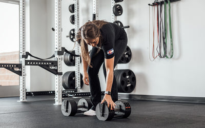 Female lifter selecting the weight on a REP Fitness QuickDraw Adjustable Dumbbell.