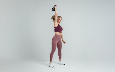 Athlete holding a kettlebell over their head while wearing the REP Rhea Tank in Wine