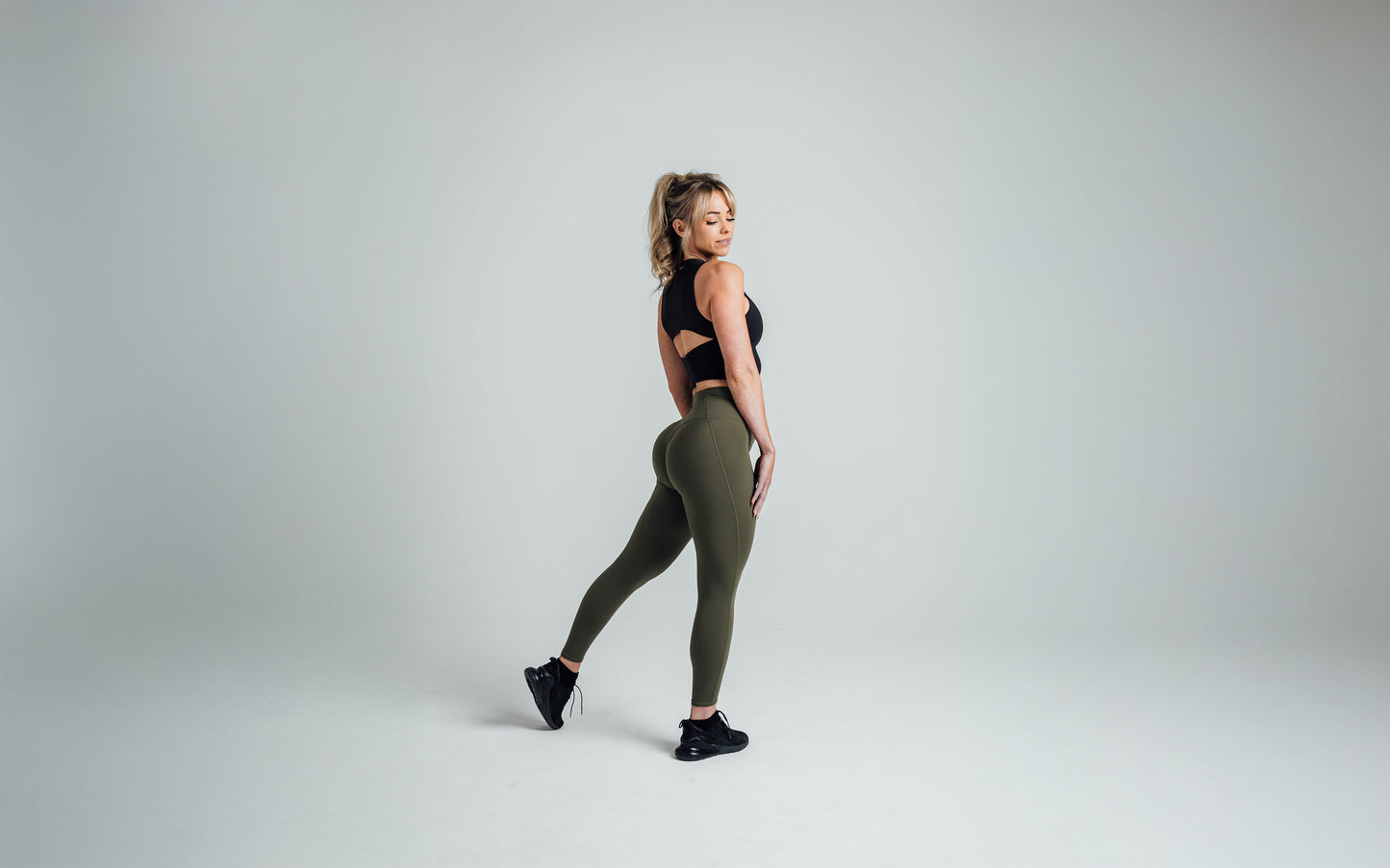Side shot of an athlete striking a pose while wearing the REP Rhea Tank in Black