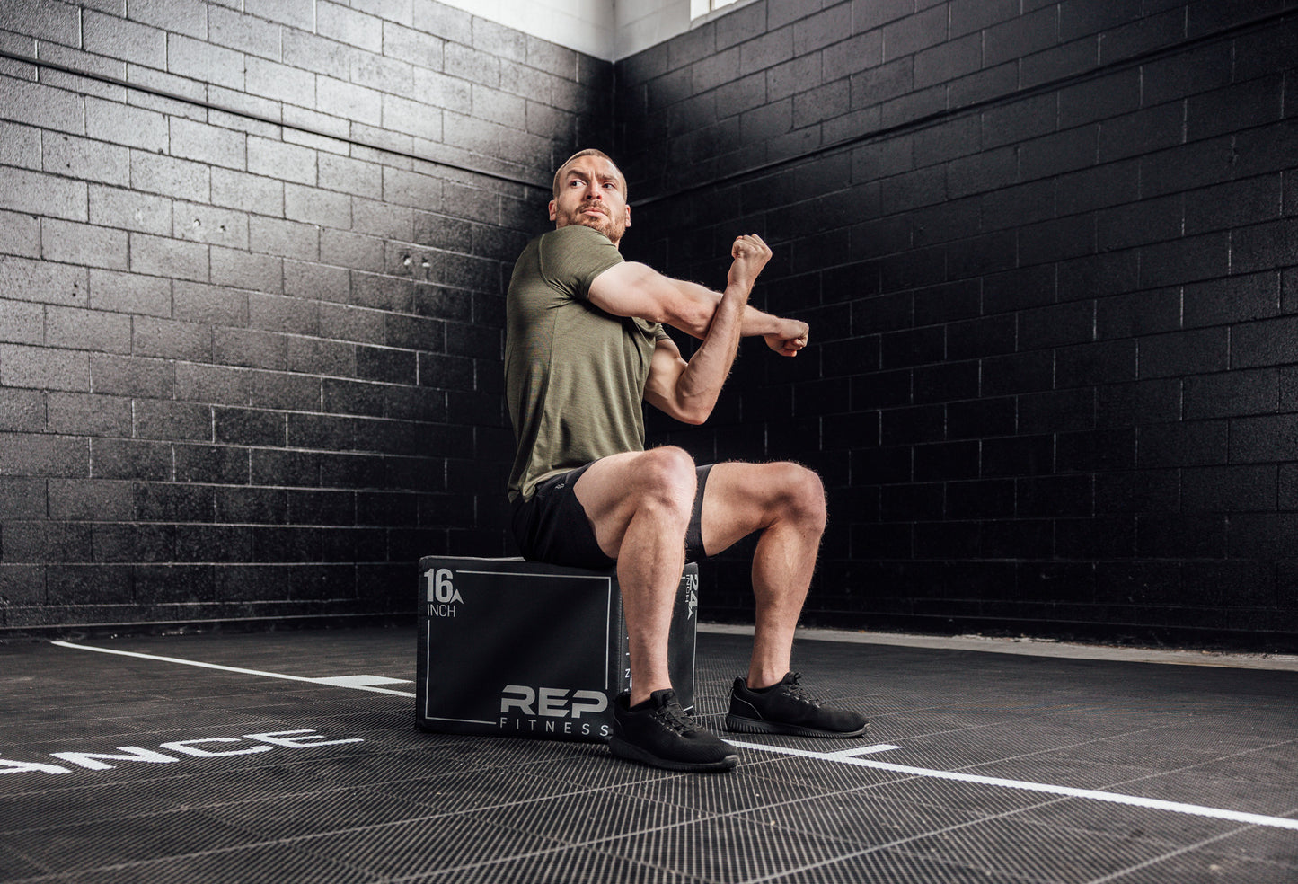 Athlete stretching in a Heather Olive Sigmatech Shirt. Also available in Heather Navy, Heather Black.