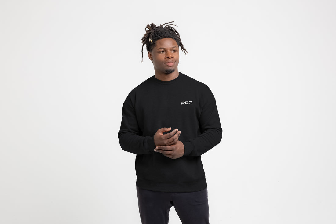 The REP Fitness Unisex REP® Crewneck Sweatshirt in Black/White front, hands clasped