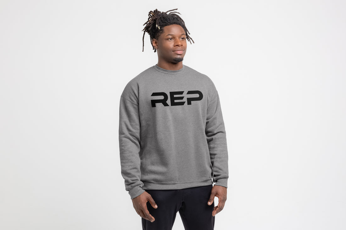 The REP Fitness Unisex Daily Driver Crewneck Sweatshirt in Heather Gray/Black front, on model