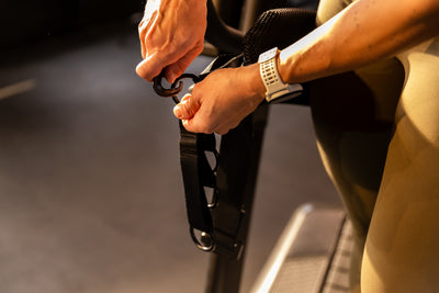 Athlete connecting the Strive Curved Treadmill Straps to the Belt Squat Belt