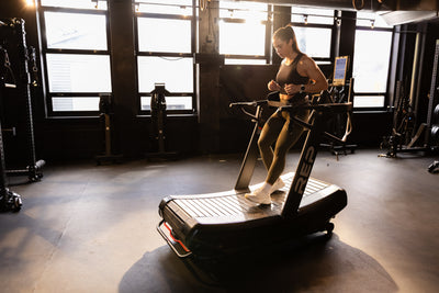 Athlete reverse sled walking with the belt squat belt on the Strive Curved Treadmill
