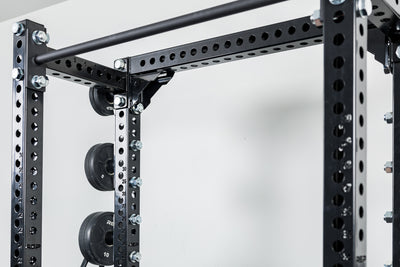 Close-Up of Compact Logo Plate Crossmember 2.0 on a REP power rack with weights on a white background.