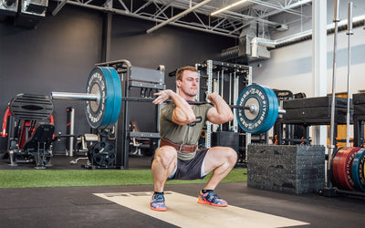 Athlete in the bottom catch position of a clean and jerk while wearing a brown REP Leather Olympic Lifting Belt.