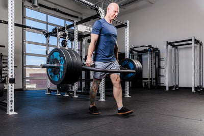 Man performing a heavy carry with the Fixed Open trap bar in a gym setting