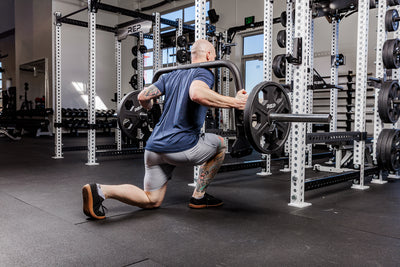 Man performing lunges with the Fixed Open trap bar in a gym setting