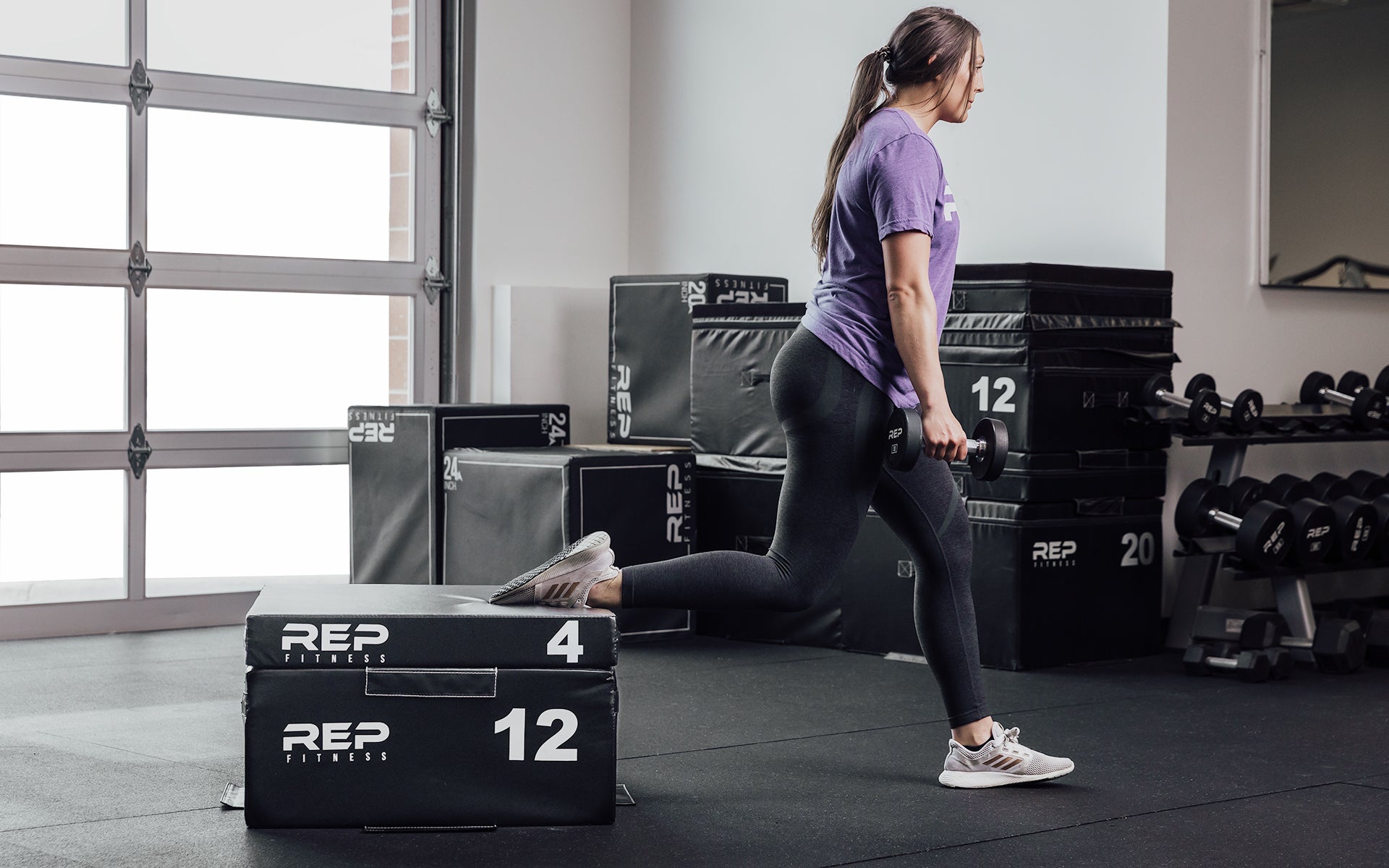 Female athlete performing a split squat with her back foot elevated on a 12