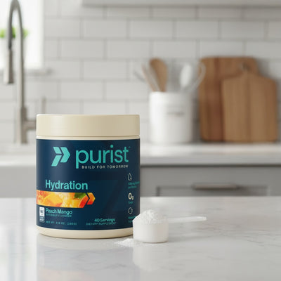 Purist® Hydration peach mango container on a kitchen counter with a scoop of powder.