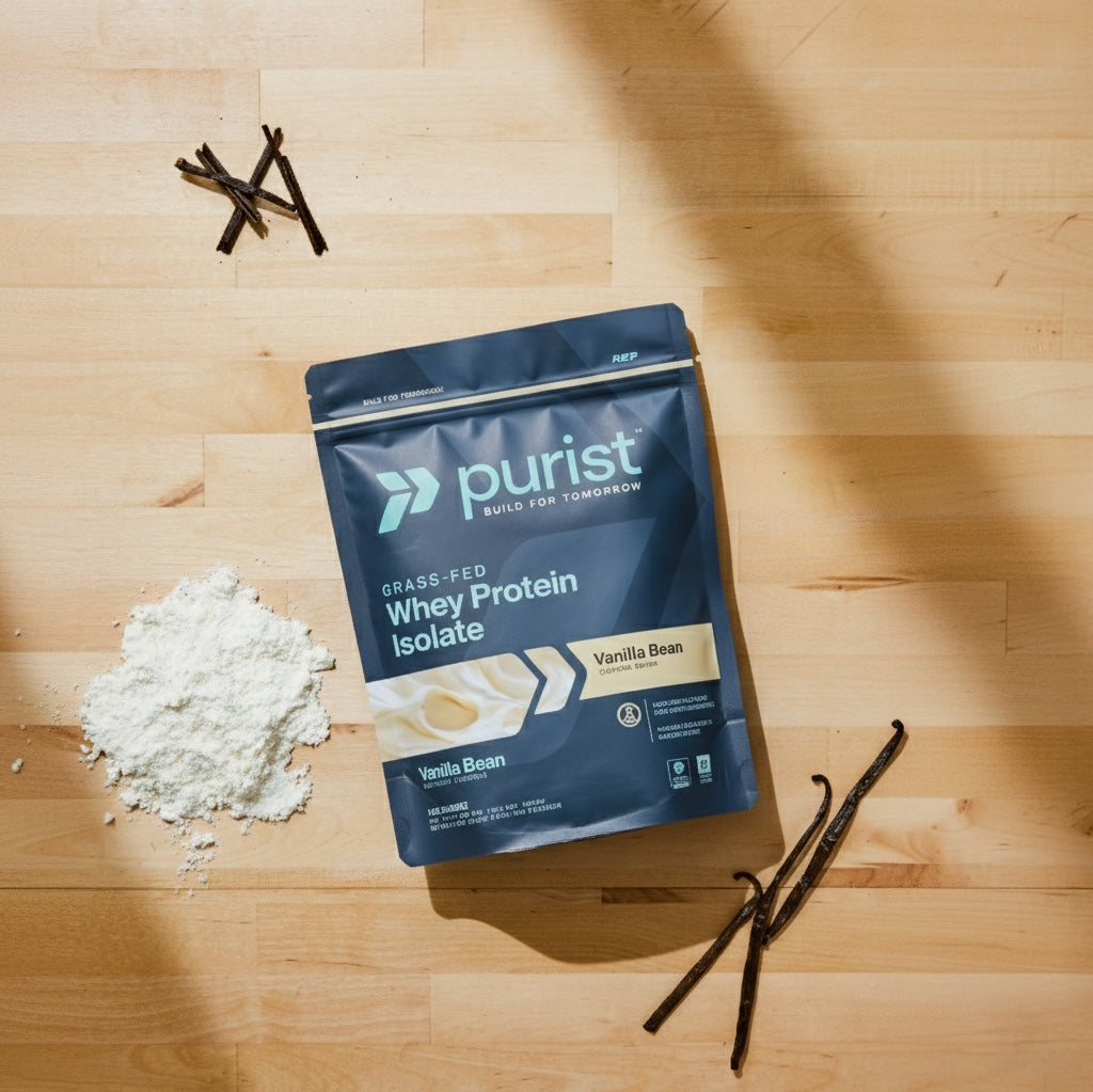 Purist whey protein isolate vanilla bean package on a wooden surface with vanilla beans and protein powder.