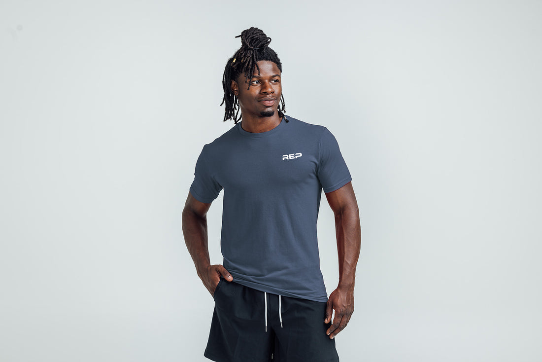 The REP Fitness Men's USA Tri-Blend Crew T-Shirt in Heather Navy/White front, hands in pockets