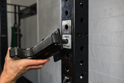 Close-up of an athlete attaching a J-cup to a rack upright over the front squat Power Rack Magnetic Position Marker